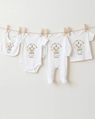 A collection of baby clothes, including onesies and bibs, hanging on a clothesline.