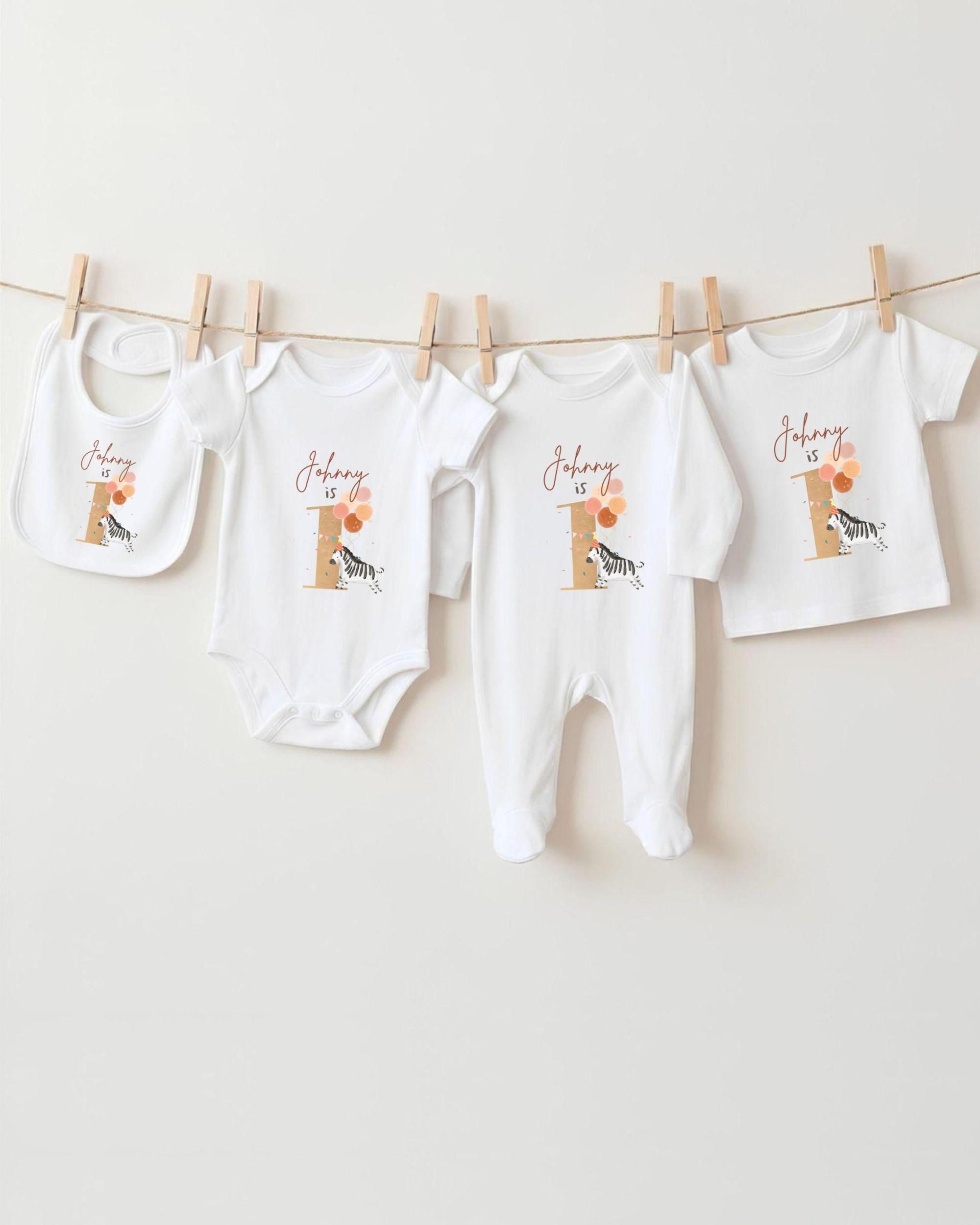 A collection of baby clothes, including onesies and bibs, hanging on a clothesline.