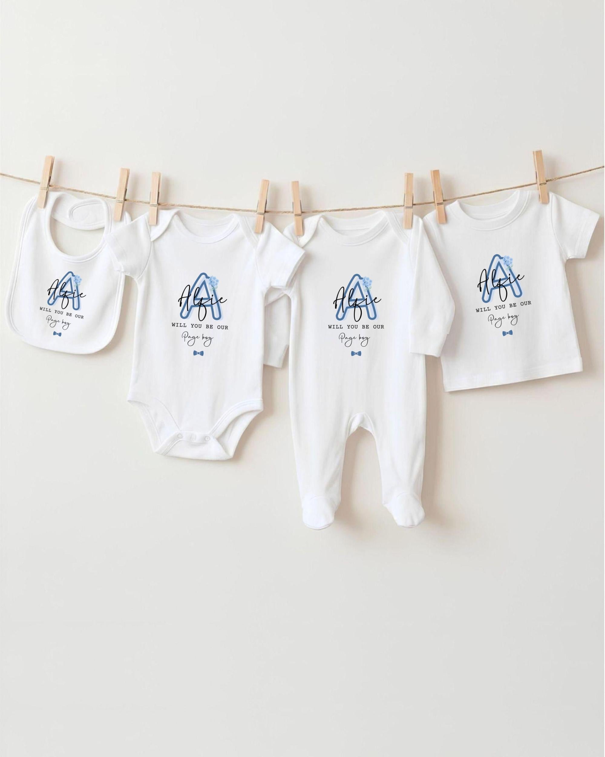 A row of white baby clothes, including onesies and bibs, hanging on a clothesline.