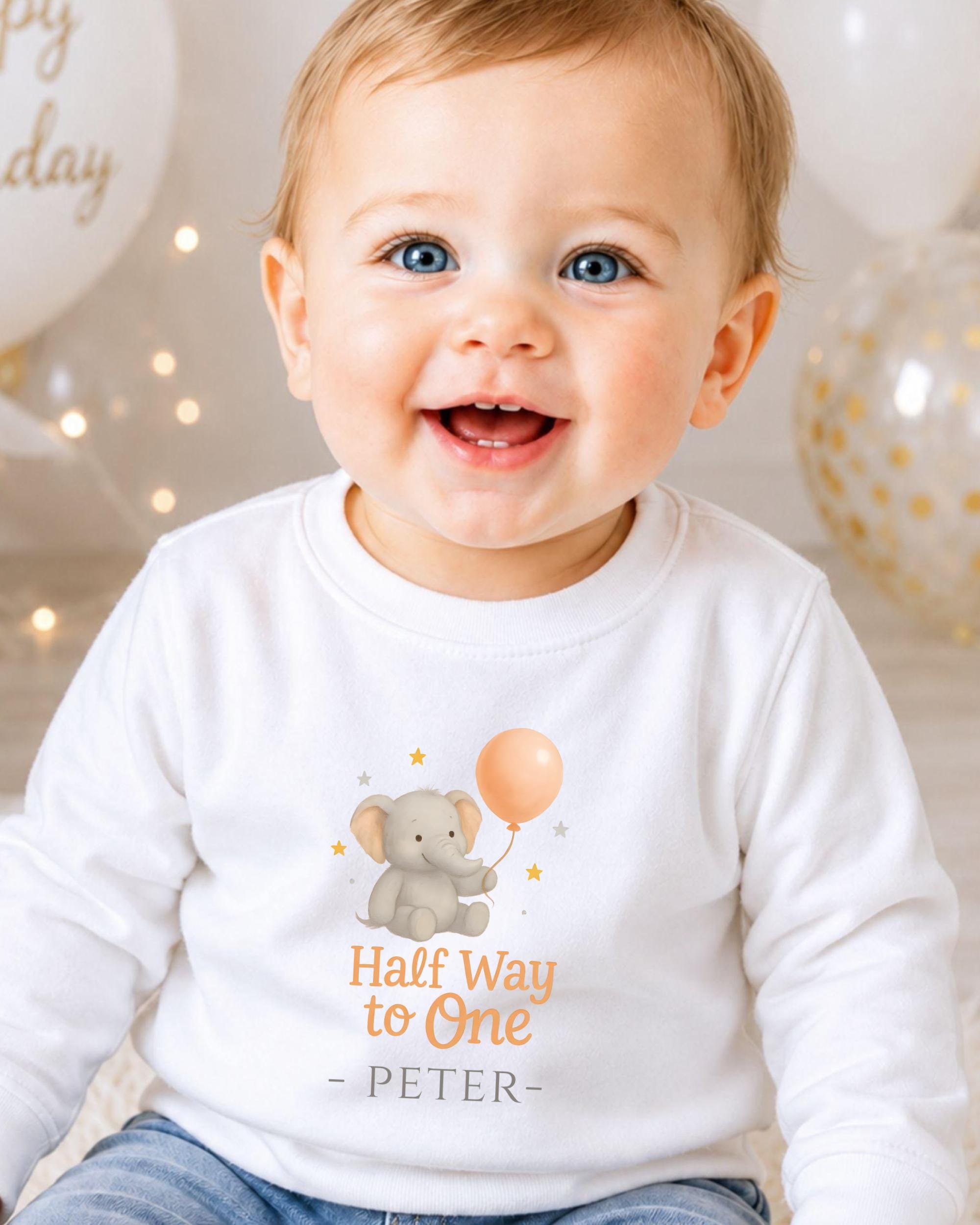A smiling baby boy wearing a white shirt with an elephant and balloon graphic, and the text "Half Way to One - Peter" printed on it.