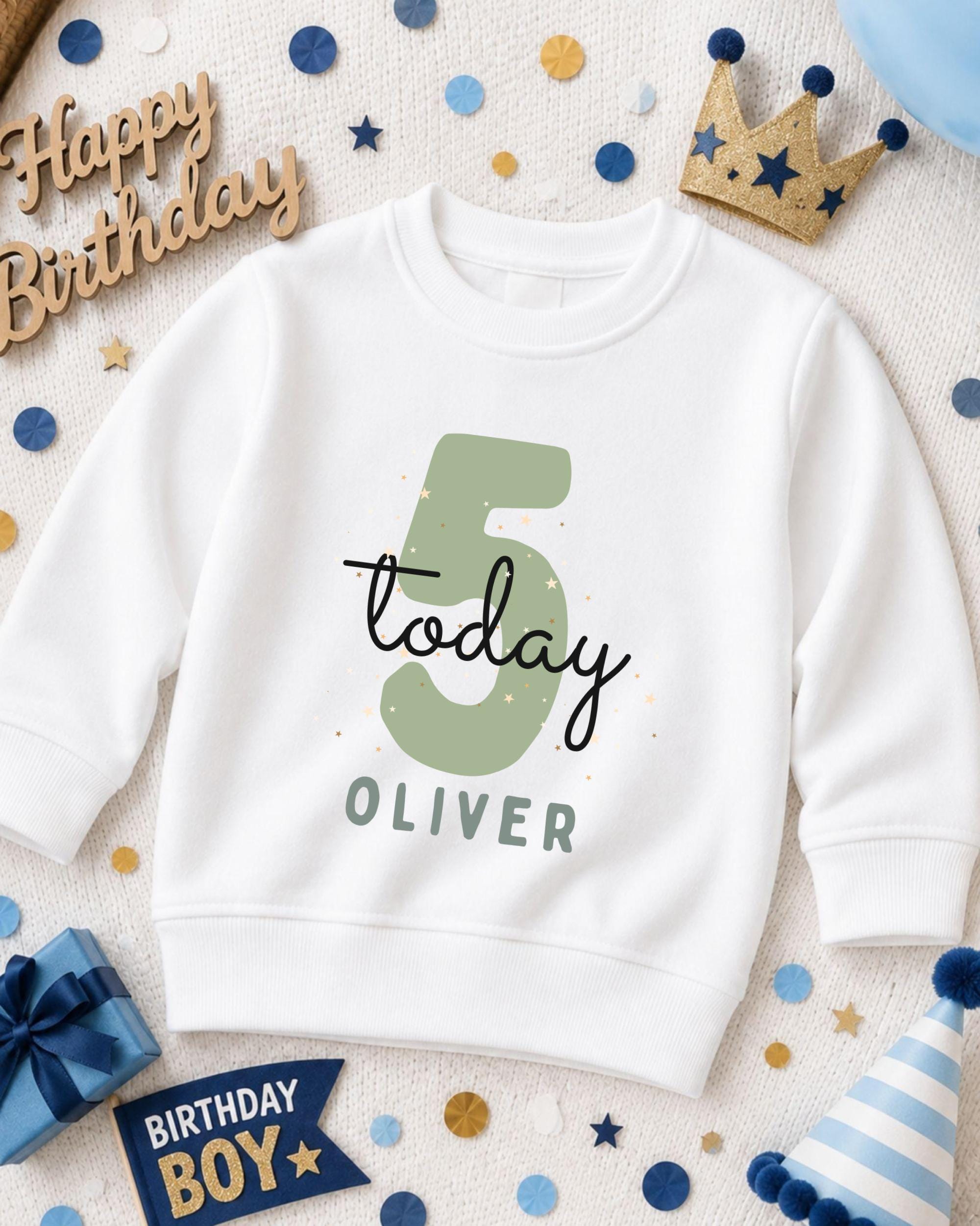 A white sweatshirt with the number 5 and the text "Today Oliver" printed on it, surrounded by birthday decorations such as a crown, confetti, and a birthday hat.