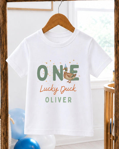 A white t-shirt with a graphic design featuring a cartoon duck and the text "One Lucky Duck Oliver" printed on it.
