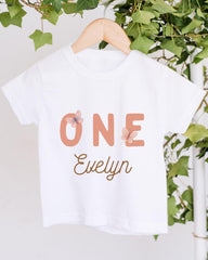 A white t-shirt with the text "ONE Evelyn" printed on it, along with a butterfly design.