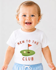 A smiling baby wearing a white t-shirt with the text "NEW TO THE CLUB" and a golf hole graphic.