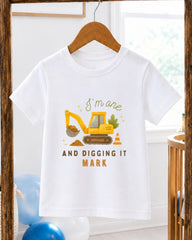 A white t-shirt with a graphic design of a yellow construction vehicle and the text "I'm one AND digging it MARK" printed on it.