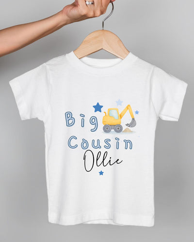 A white t-shirt with a graphic design of a yellow construction vehicle and the text "Big Cousin Ollie" printed on it.