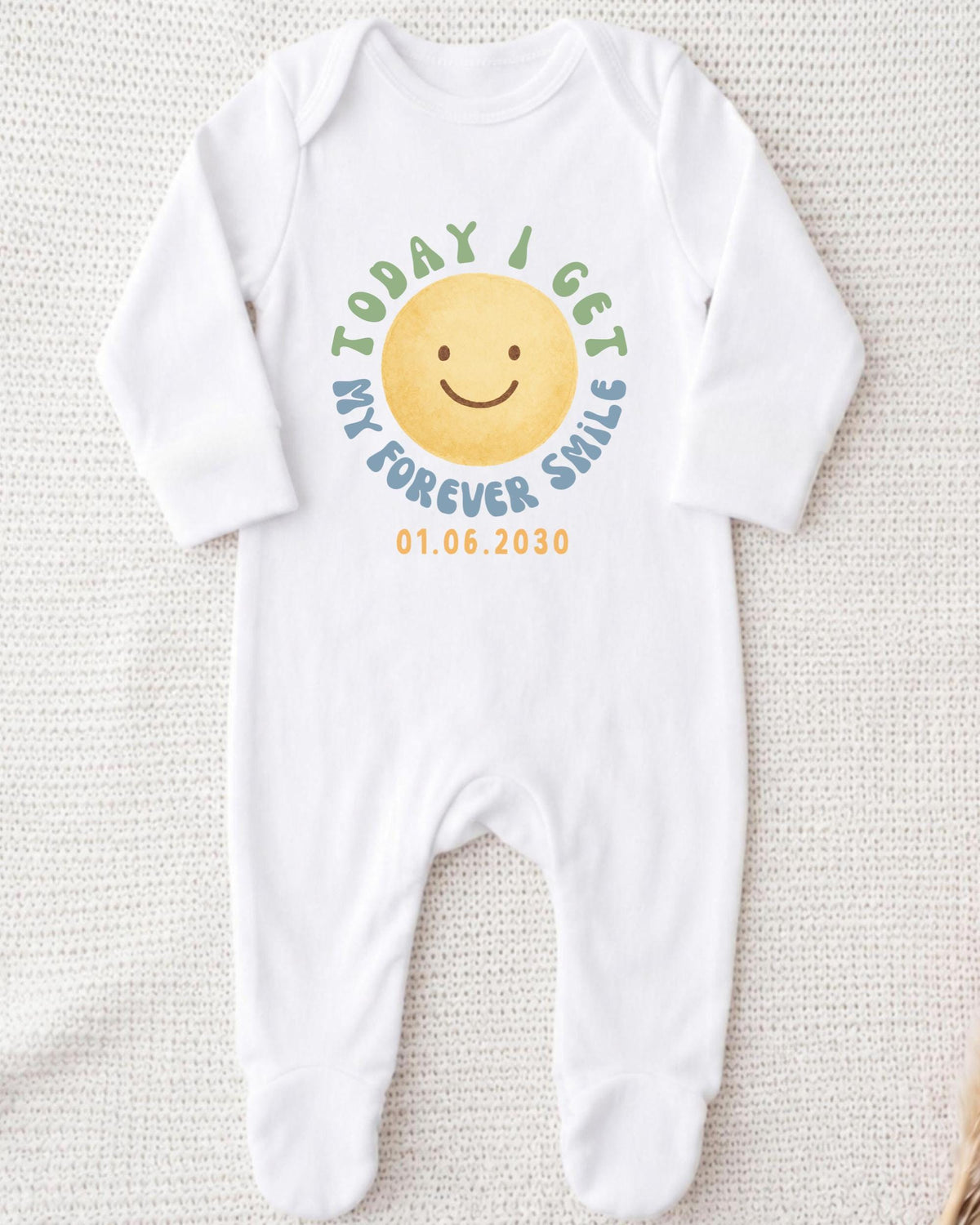 A white onesie with a smiley face design and text printed on it.