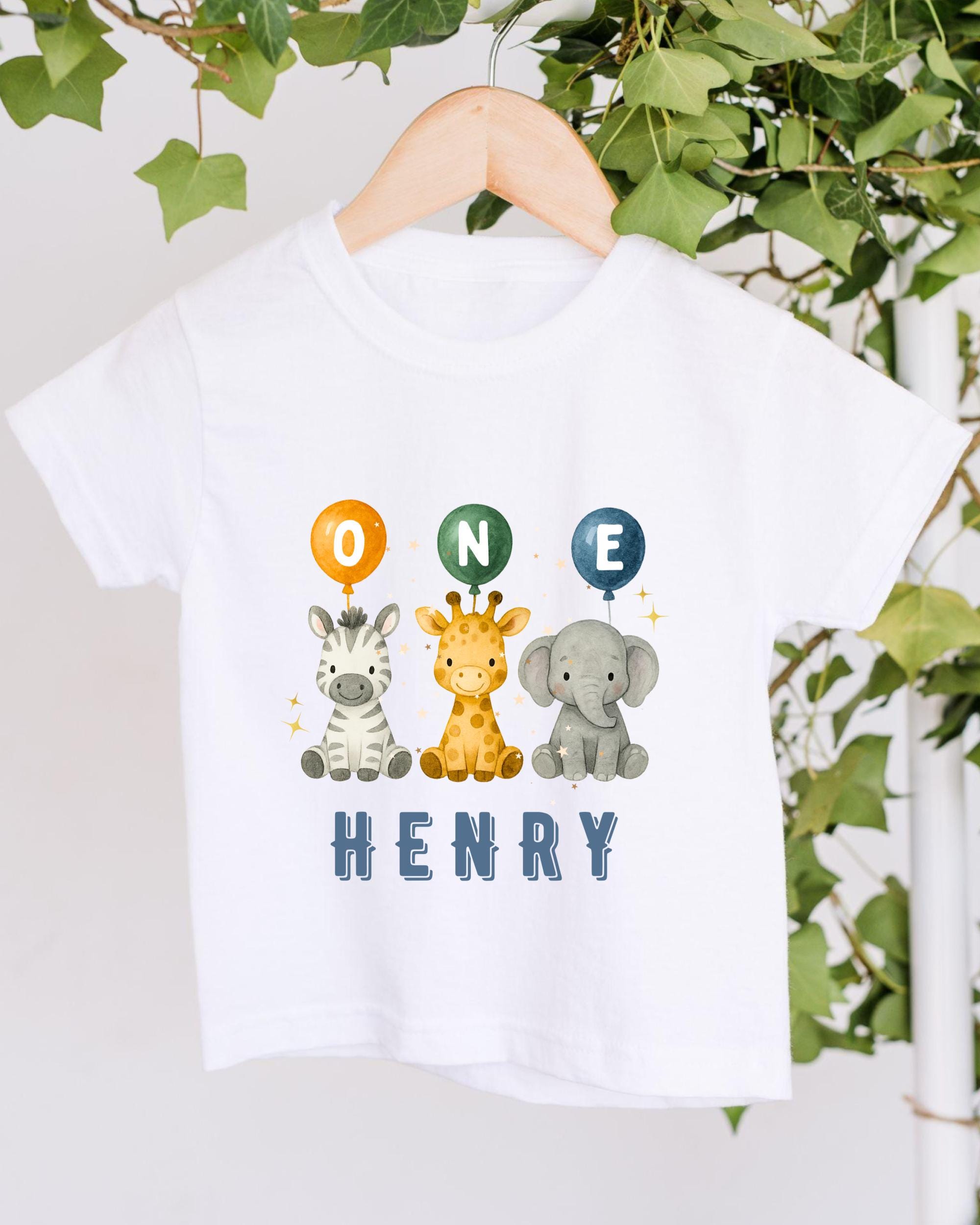 A white t-shirt with a graphic design featuring three cartoon animals - a giraffe, a zebra, and an elephant - along with the text "ONE HENRY" printed on it.