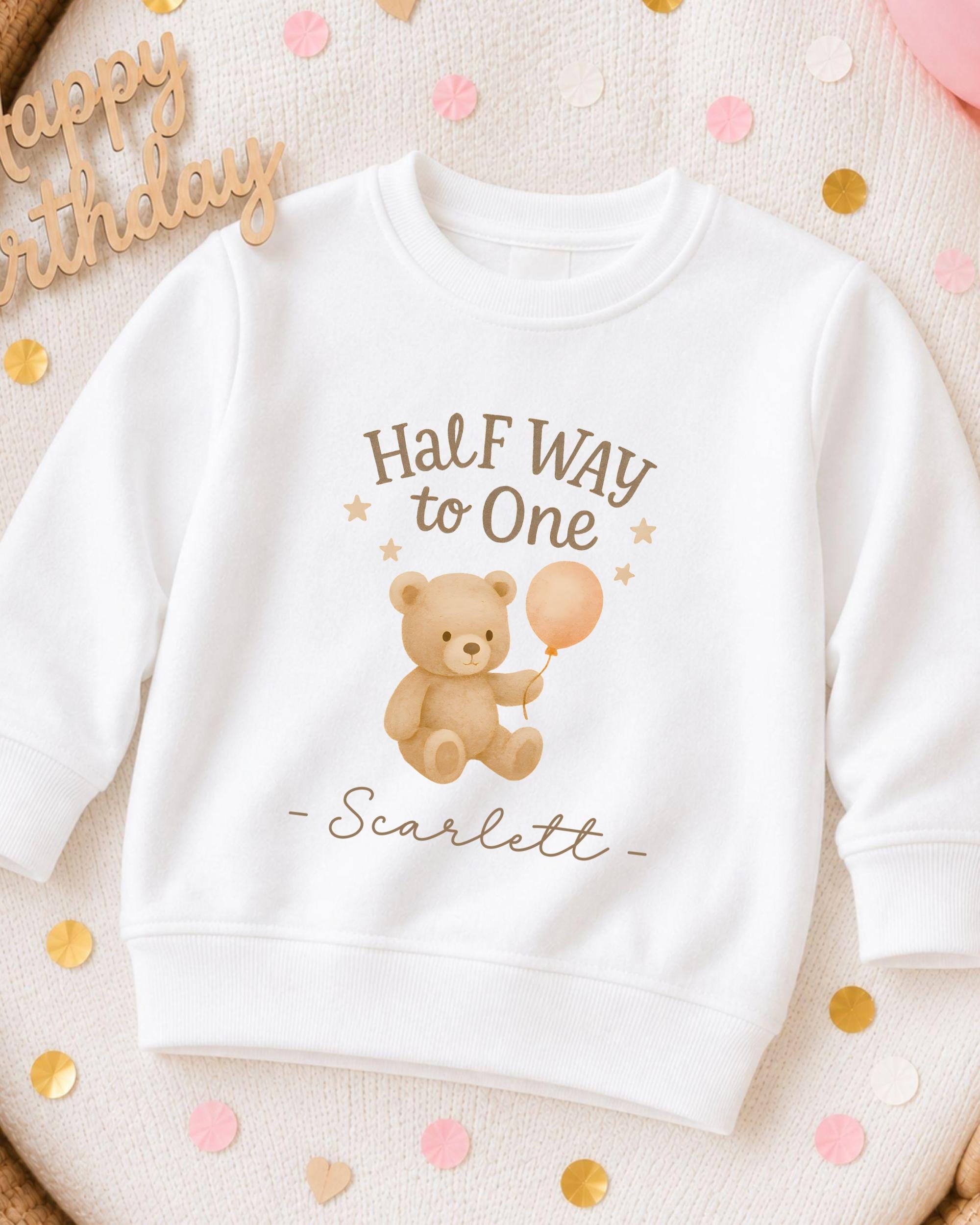 A white sweatshirt with a teddy bear and a balloon printed on it, along with the text "Half Way to One -scarlett".
