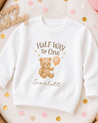 A white sweatshirt with a teddy bear and a balloon printed on it, along with the text "Half Way to One -scarlett".