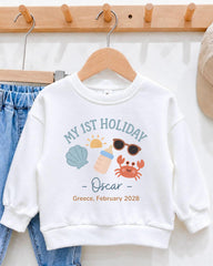 A white sweater with a graphic design on it, hanging on a wooden hanger.