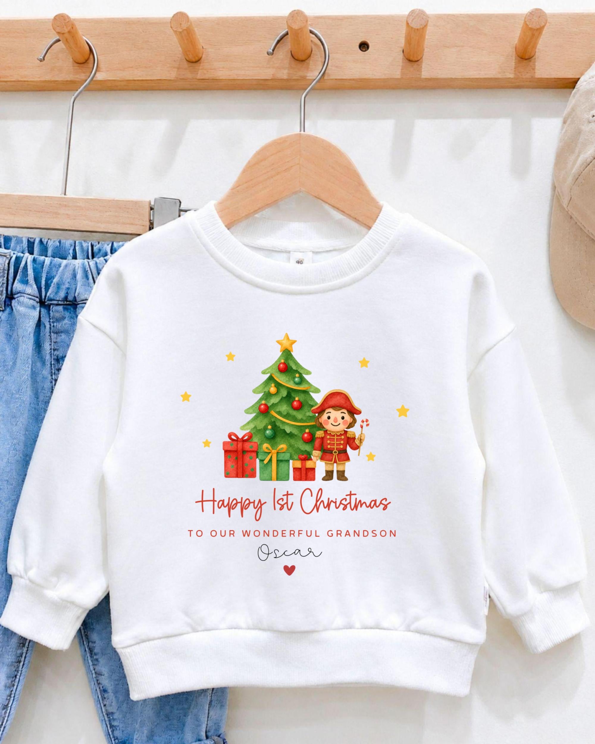 A white sweatshirt with a Christmas-themed design hanging on a wooden hanger.