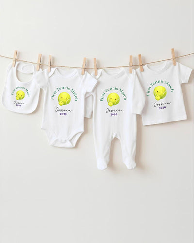 A row of white baby clothes with tennis ball designs hanging on a clothesline.