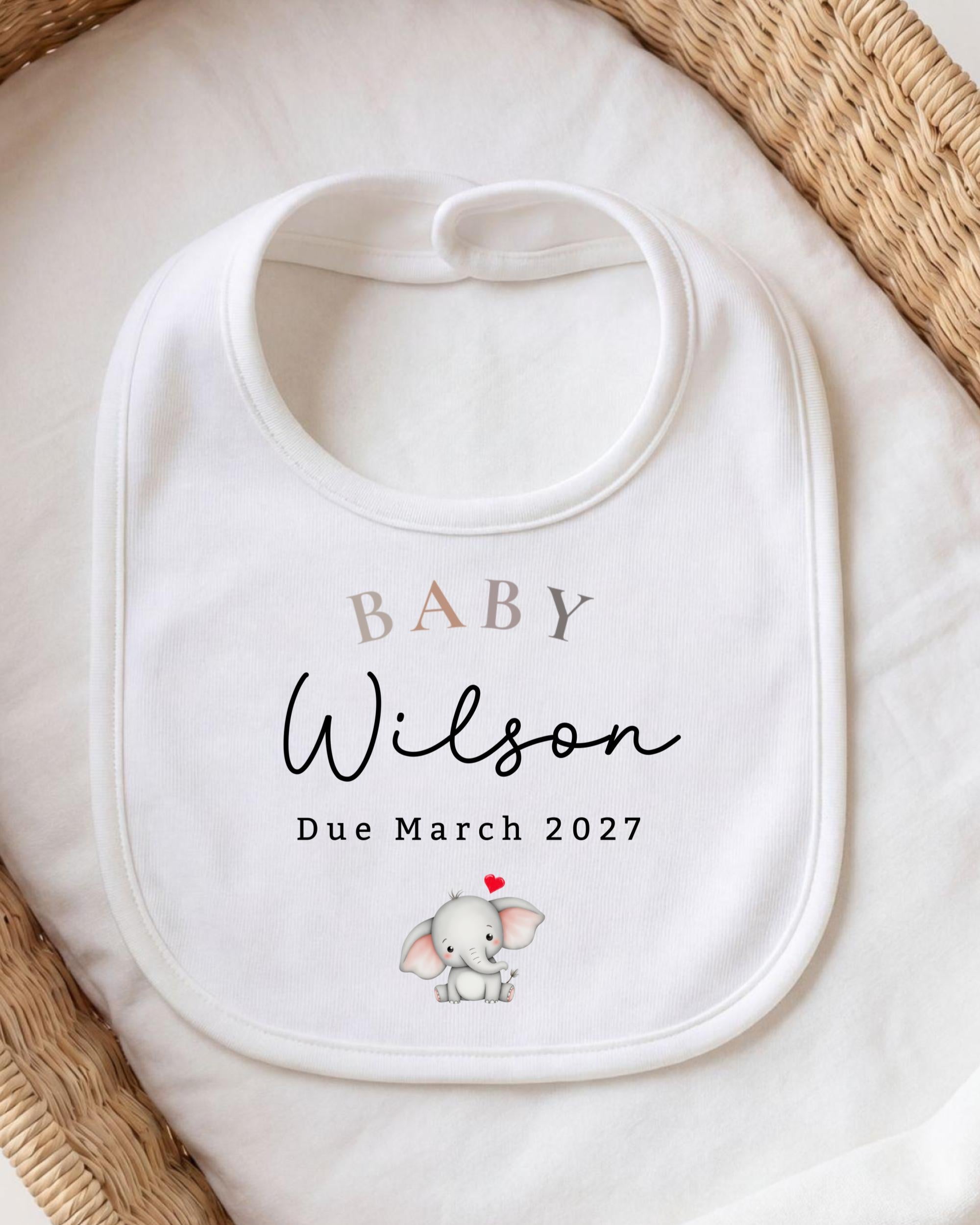 A white baby bib with the name "Baby Wilson" and the date "Due March 2027" printed on it, along with an illustration of a baby elephant.