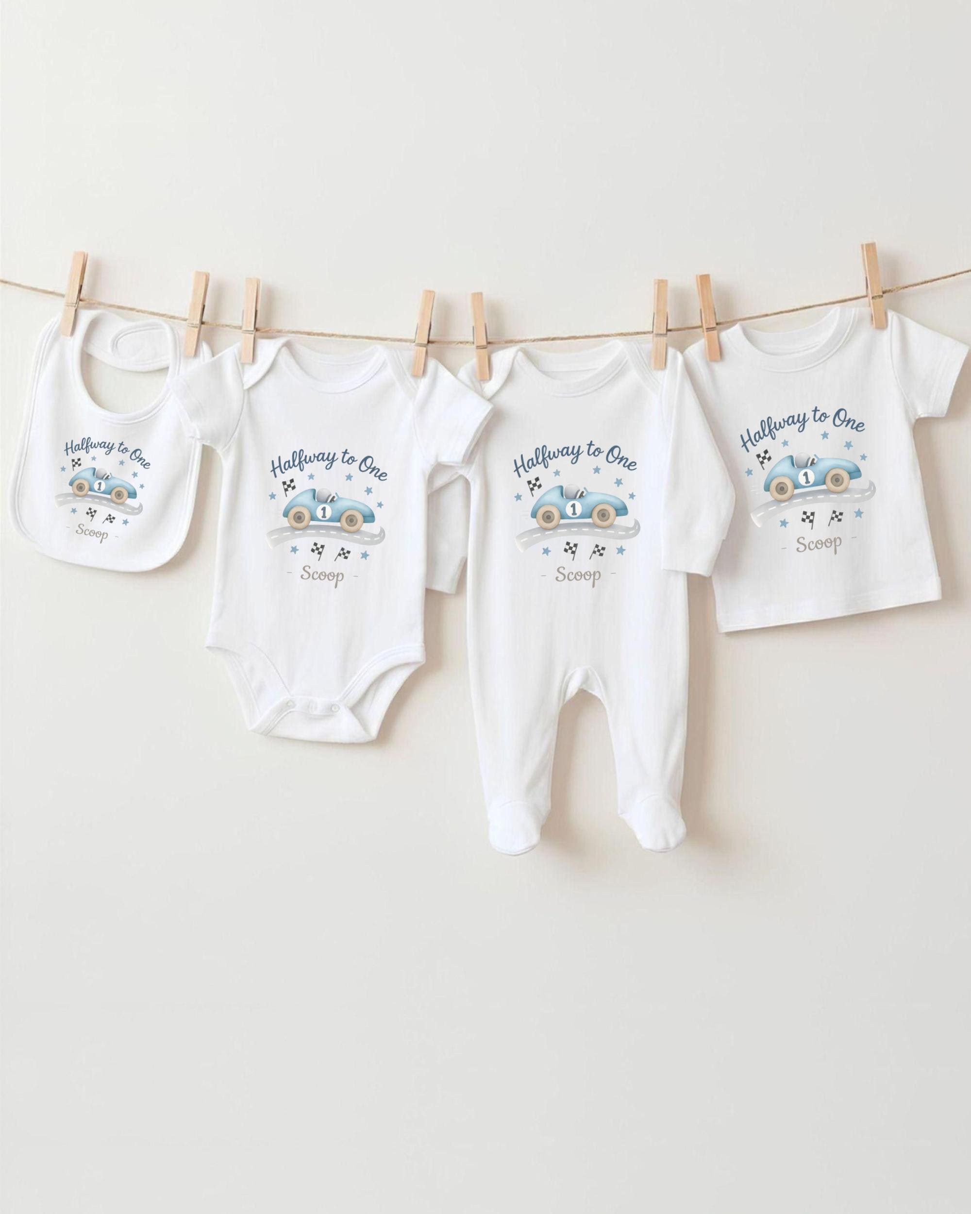 A collection of baby clothes, including onesies and pants, hanging on a clothesline.