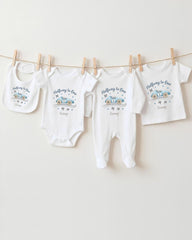 A collection of baby clothes, including onesies and pants, hanging on a clothesline.