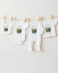 A collection of four white baby clothes, including onesies and bibs, hanging on a clothesline.