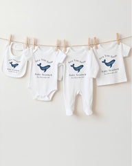 a collection of baby clothing items, including onesies and pajamas, hanging on a clothesline.