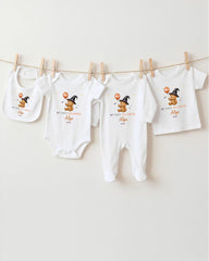A collection of white baby clothes, including onesies and pajamas, hanging on a clothesline.