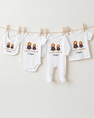 A row of white baby clothes with the name "Little Cousin Harper" printed on them, hanging on a clothesline.