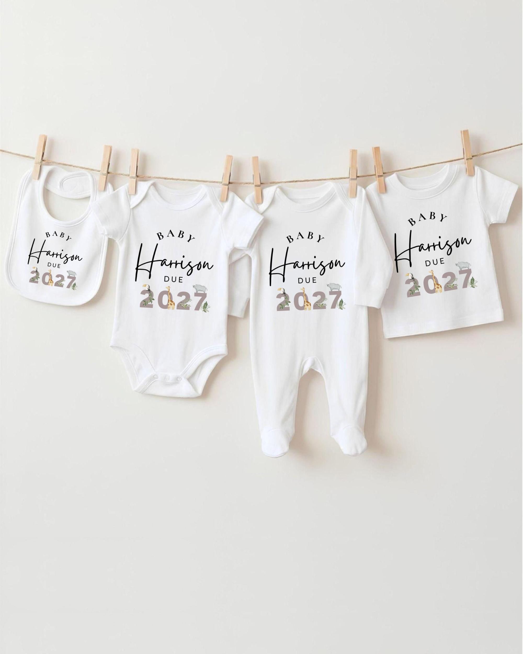 A row of white baby clothes hanging on a clothesline, each with a unique size and the text "BABY Harrison Due 2027" printed on them.
