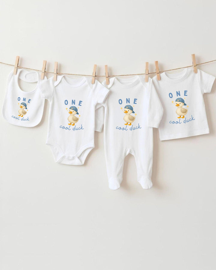A collection of baby clothes, including bodysuits and bibs, hanging on a clothesline.