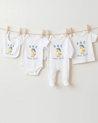 A collection of baby clothes, including onesies and bibs, hanging on a clothesline.