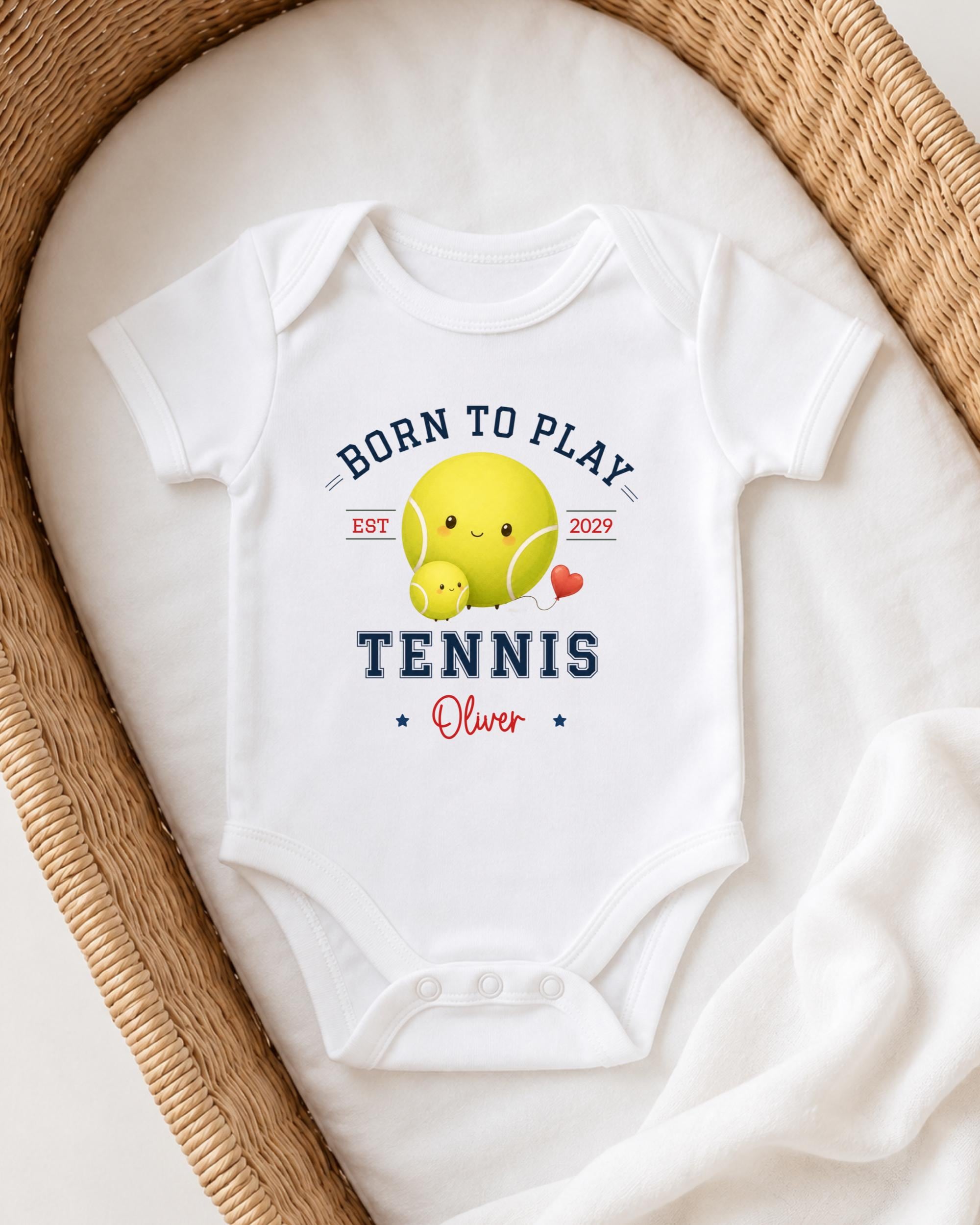 A white onesie with a tennis ball and a smiling tennis ball design, along with the text "Born to play TENNIS Oliver" printed on it.