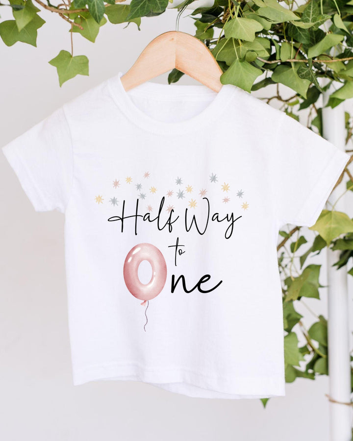 A white t-shirt with a graphic design and text printed on it, hanging on a wooden hanger.