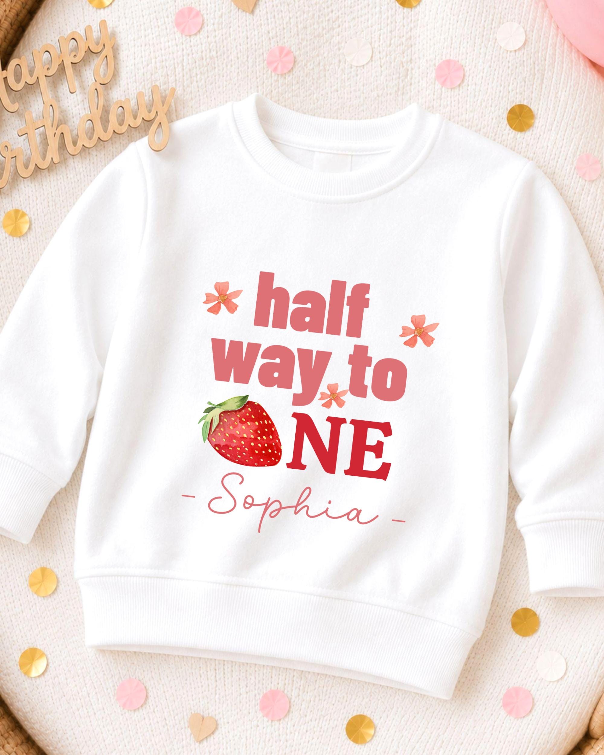 A white sweatshirt with a personalized text and a strawberry graphic printed on it.