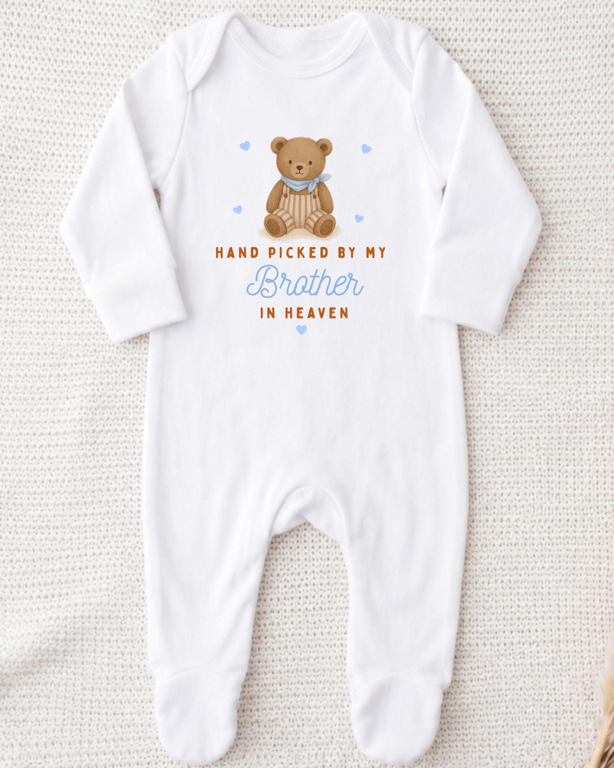 A white onesie with a teddy bear graphic and text that reads "Hand picked by my Brother in Heaven".