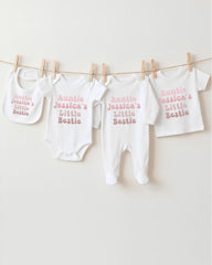 A row of four white baby clothes, including bibs and onesies, hanging on a clothesline.
