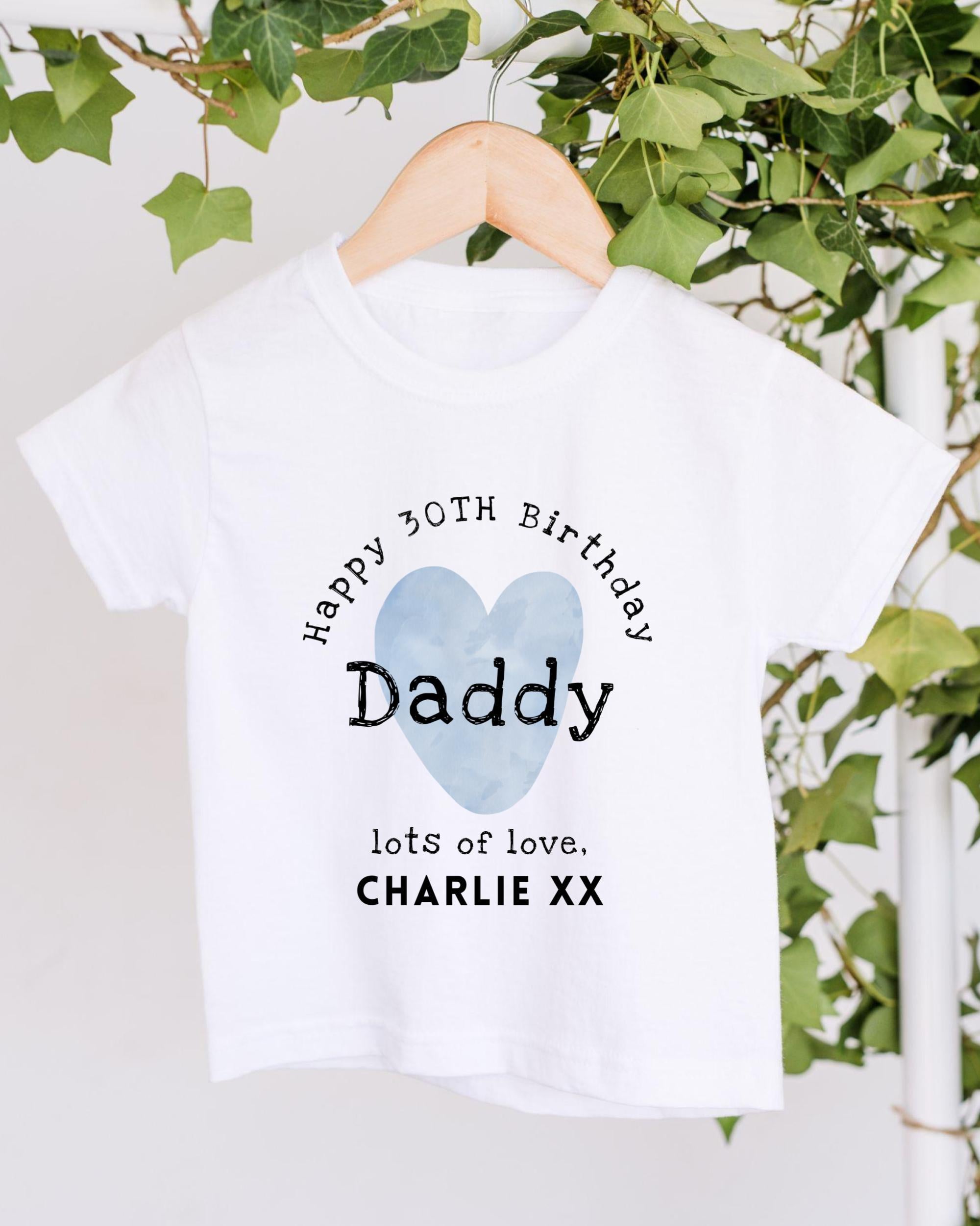 A white t-shirt with a graphic design that says "Happy 30th Birthday Daddy lots of love. Charlie XXX" printed on it.