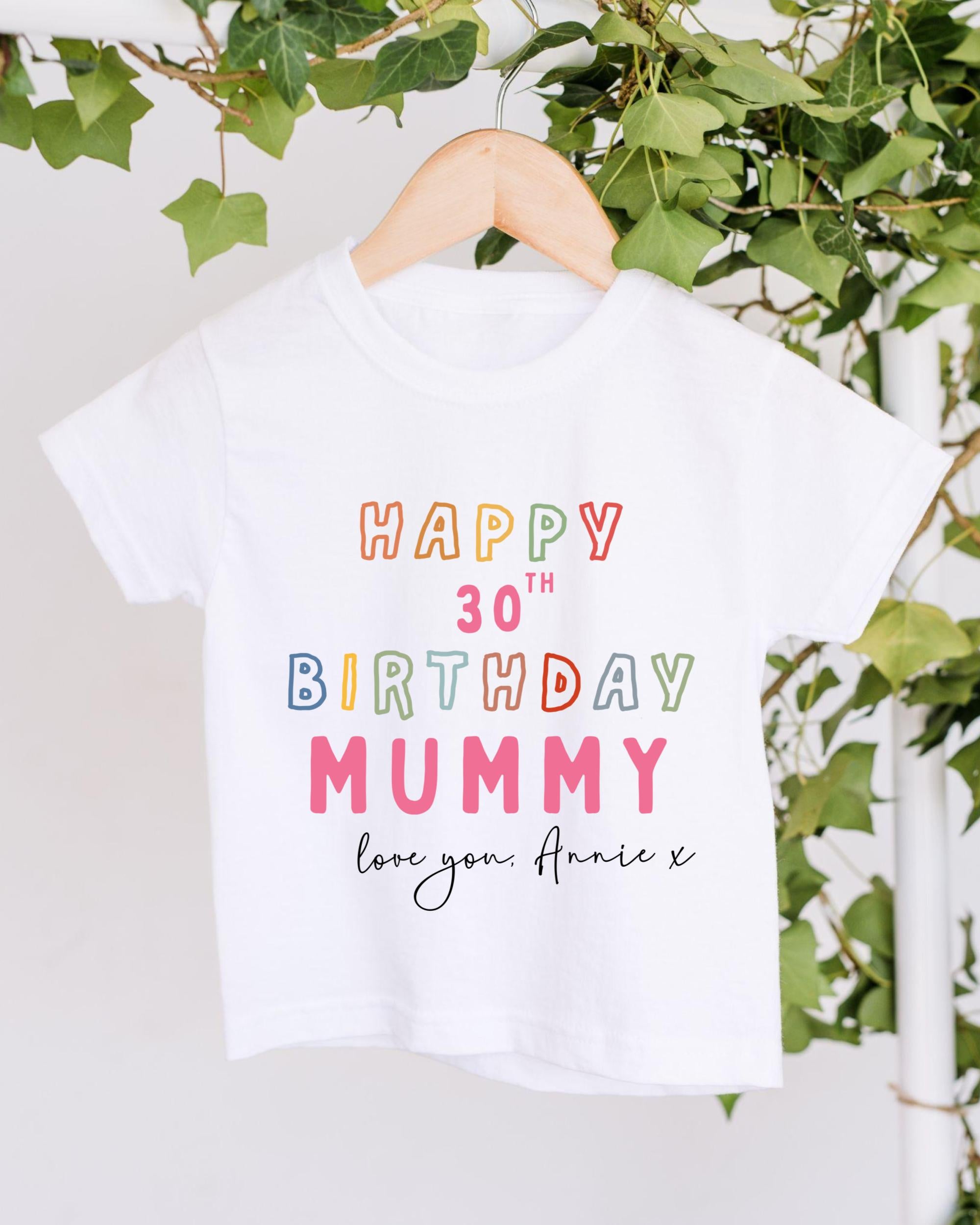 A white t-shirt with a colorful text message that reads "Happy 30th Birthday Mummy" and "Love you, Annie X" printed on it.