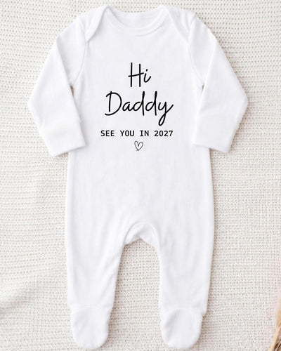 Personalised white Baby Grow with black 'Hi Daddy See You In 2027' lettering and an outline heart for a Daddy pregnancy announcement.