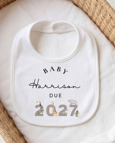 Personalised white Baby Vest, Baby Grow, Bib and T Shirt with matching 'Baby Harrison Due 2027' prints and safari animals decorating the year for a safari pregnancy announcement.