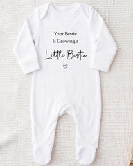 A white onesie with the text "Your Bestie Is Growing a Little Bestie" printed on it.