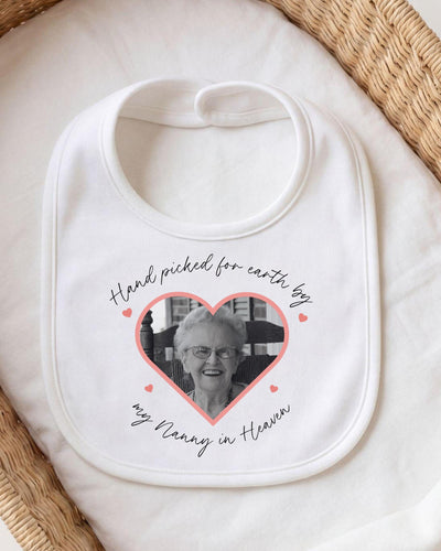 Personalised white Baby Vest, Baby Grow, Bib and T Shirt with a heart-shaped black and white photograph, pink hearts and 'Hand picked from earth by my Nanny in Heaven' script for a memorial pregnancy announcement.