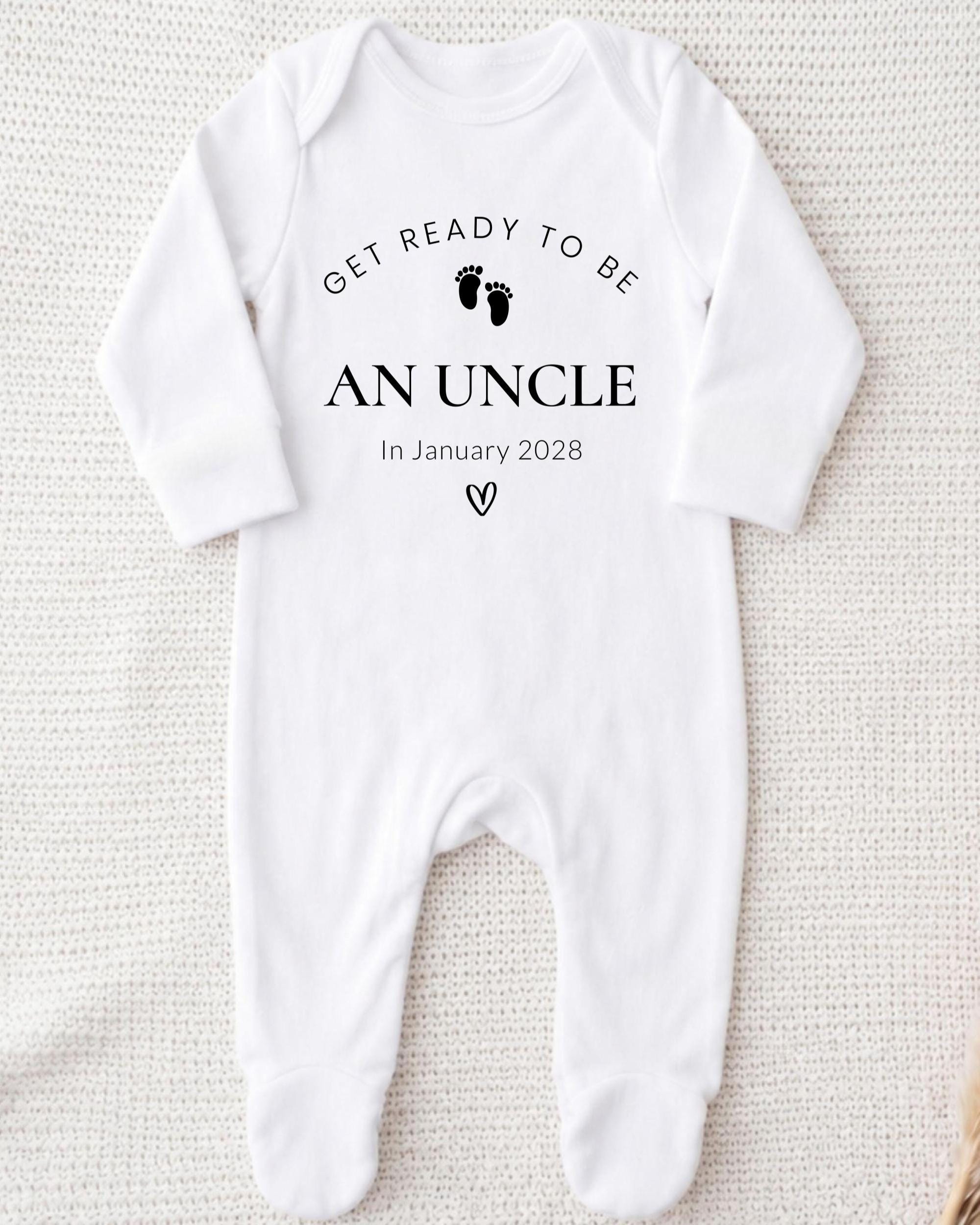 A white onesie with the text "Get ready to be an uncle In January 2028" printed on it.