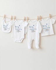 A row of four white baby clothes with blue text and stars hanging on a clothesline.