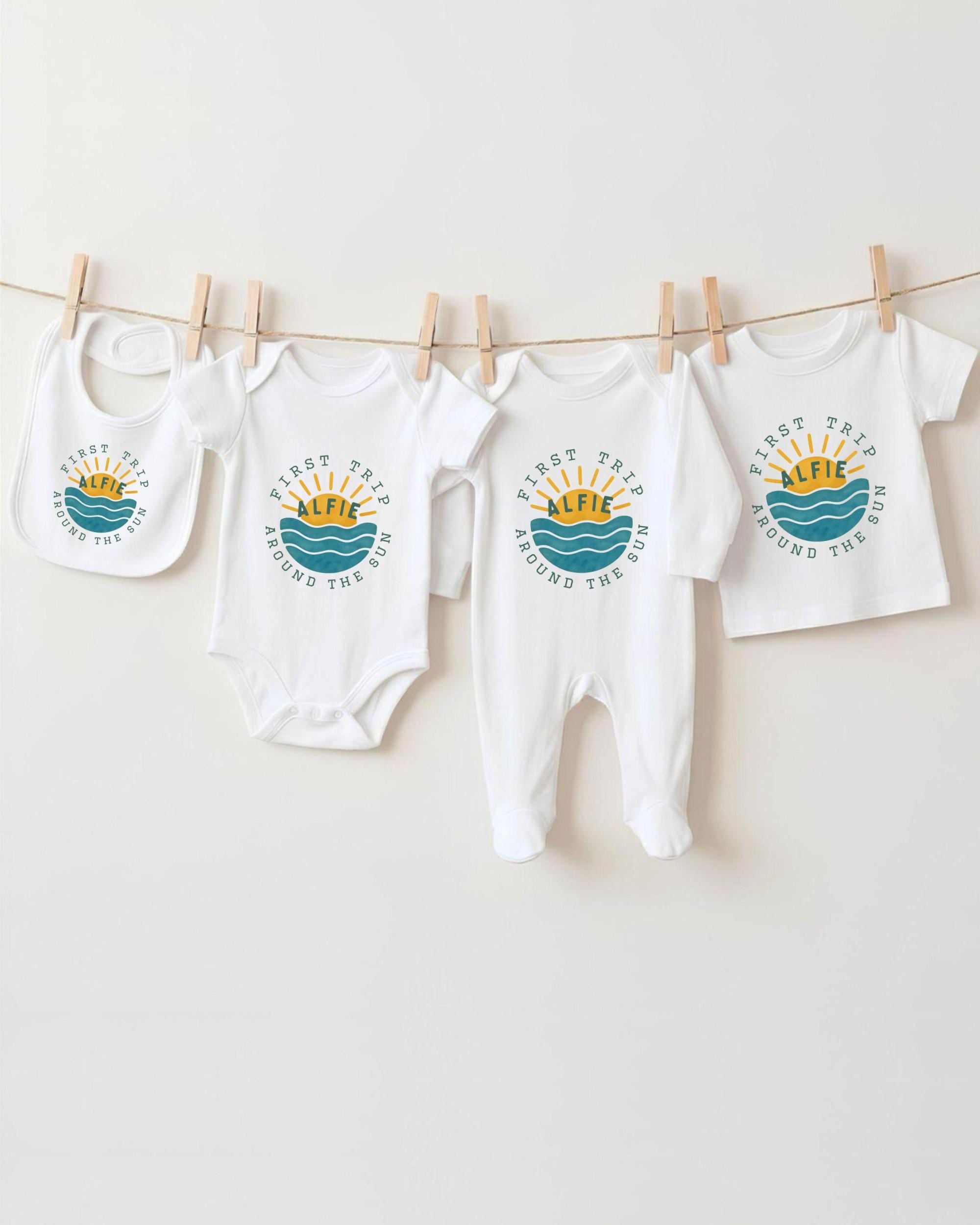 A collection of baby clothes, including onesies and bibs, hanging on a clothesline.