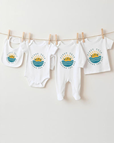 A collection of baby clothes, including bodysuits and bibs, hanging on a clothesline.