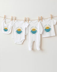 A collection of baby clothes, including onesies and bibs, hanging on a clothesline.
