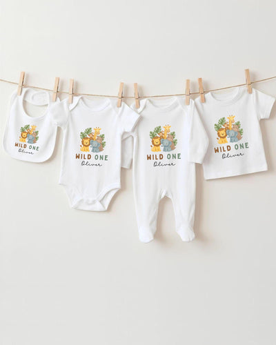 A collection of baby clothes, including bodysuits and bibs, hanging on a clothesline.