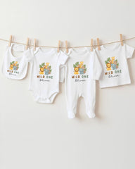 A collection of baby clothes, including onesies and bibs, hanging on a clothesline.