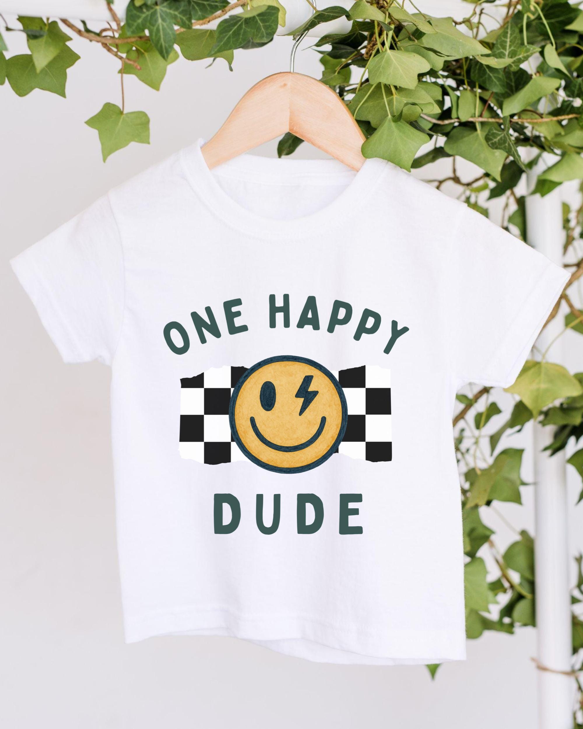 A white t-shirt with a graphic design featuring a smiling yellow smiley face and the text "ONE HAPPY DUDE" printed on it.