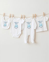 A row of four white baby clothes, including onesies and pajamas, hanging on a clothesline.