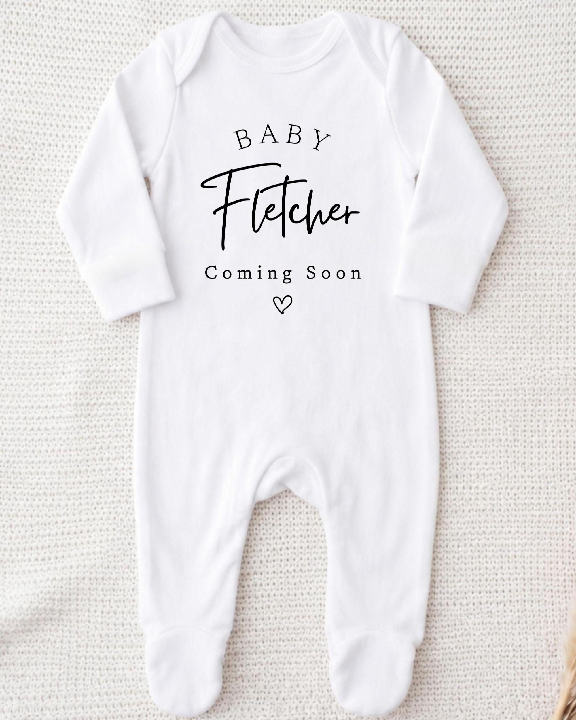 A white onesie with the text "BABY Fetcher Coming Soon" printed on it.