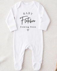 A white onesie with the text "BABY Fetcher Coming Soon" printed on it.