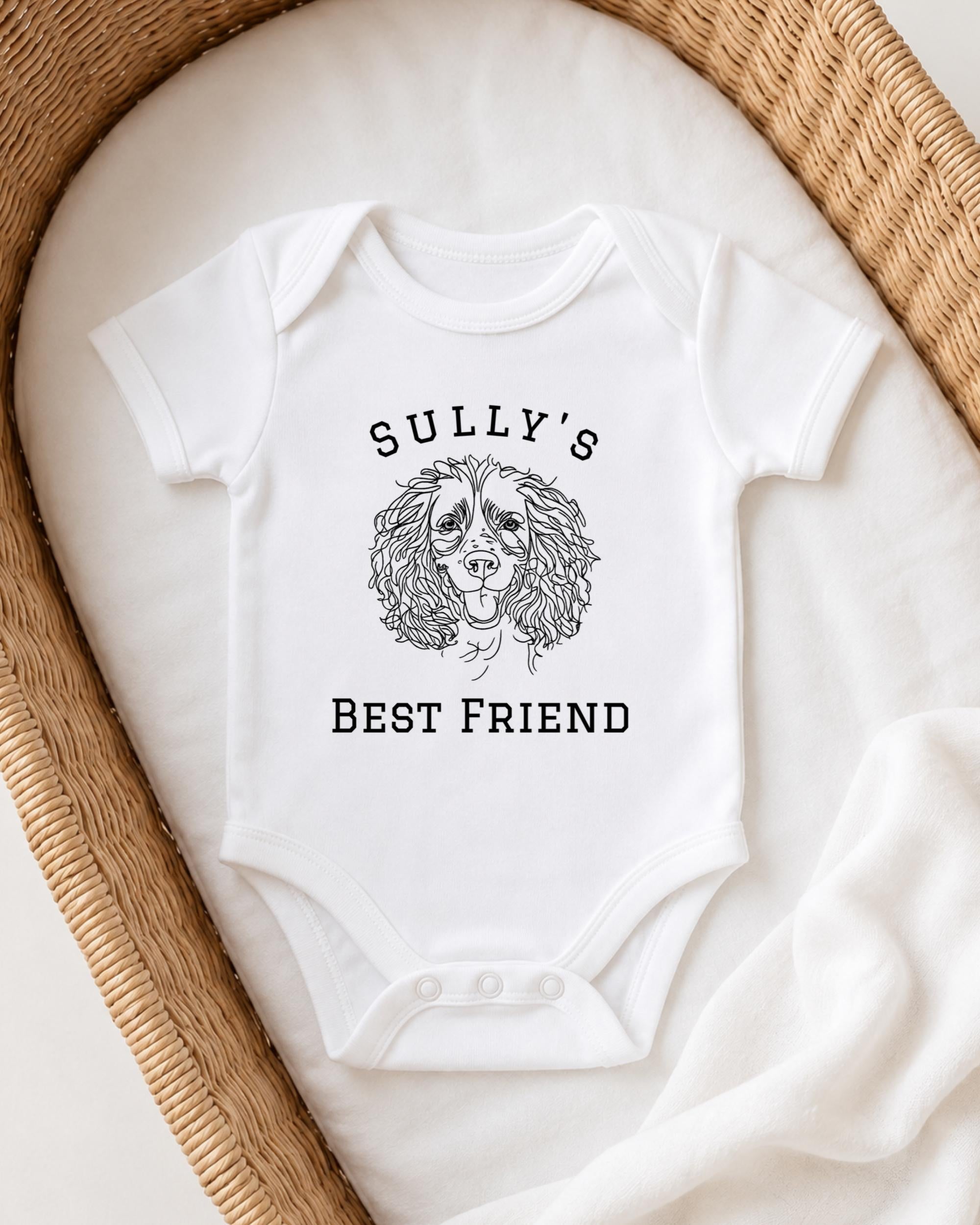 A white baby onesie with a dog illustration and the text "Sully's BEST FRIEND" printed on it.
